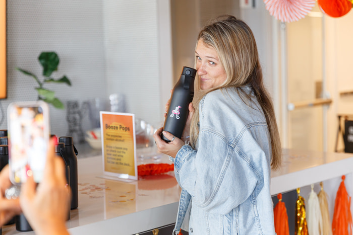 Employee posing with a branded water bottle, her photo is being taken by someone