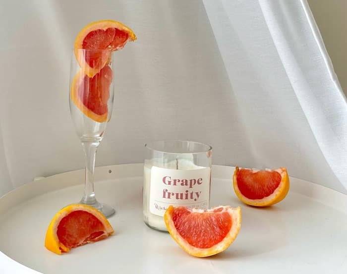 Grapefruit candle by Wickend surrounded by grapefruit slices
