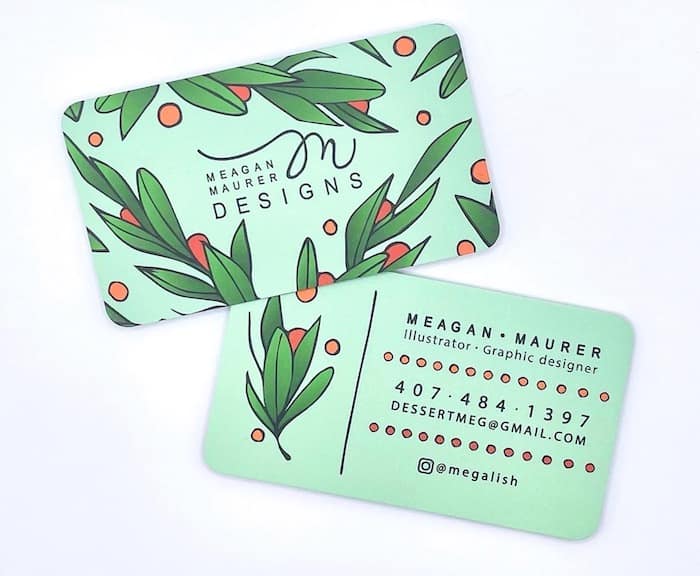 Two Meagan Maurer business cards with rounded corners. The cards are green with illustrated leaves and berries