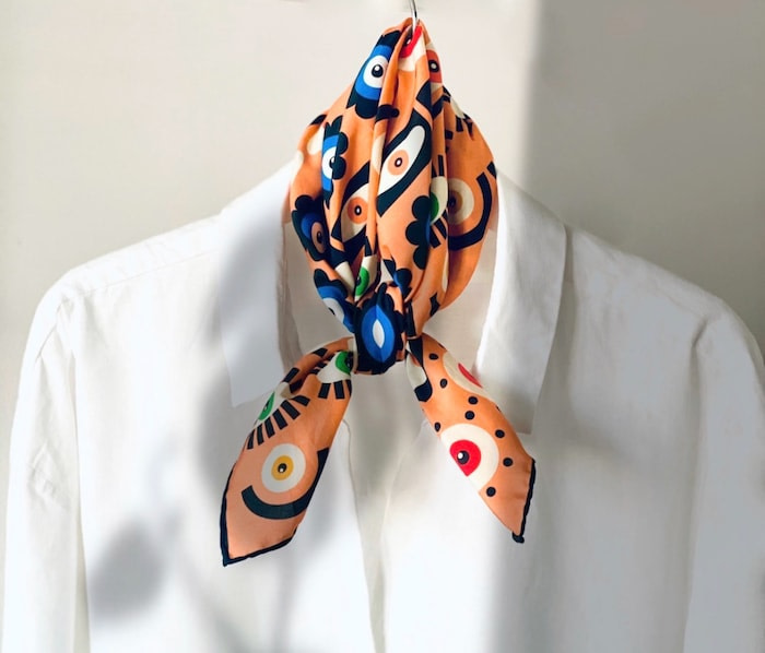 Colorful scarf with creative patterns by Mur by Ayca. The scarf is tied in a knot over a white shirt