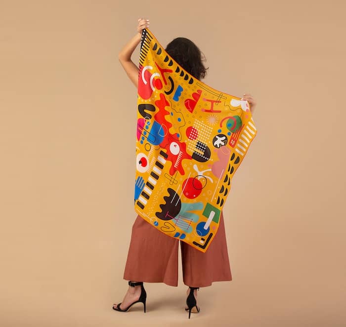 Woman holding a Mur by Ayca scarf with colorful patterns in her back