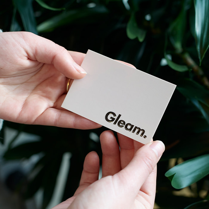 A business card that is white except for the business name, which is black with shiny spot gloss, making it pop.
