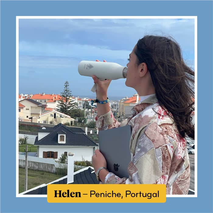 Helen, in Portugal, drinking from her water bottle as she looks out over the city of Peniche