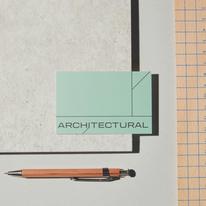An "architectural" business card with a strong font, on a table with a pencil and grid paper.