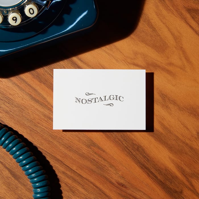 A "nostalgic" business card with an elegant and classic font, sitting next to an old rotary phone.