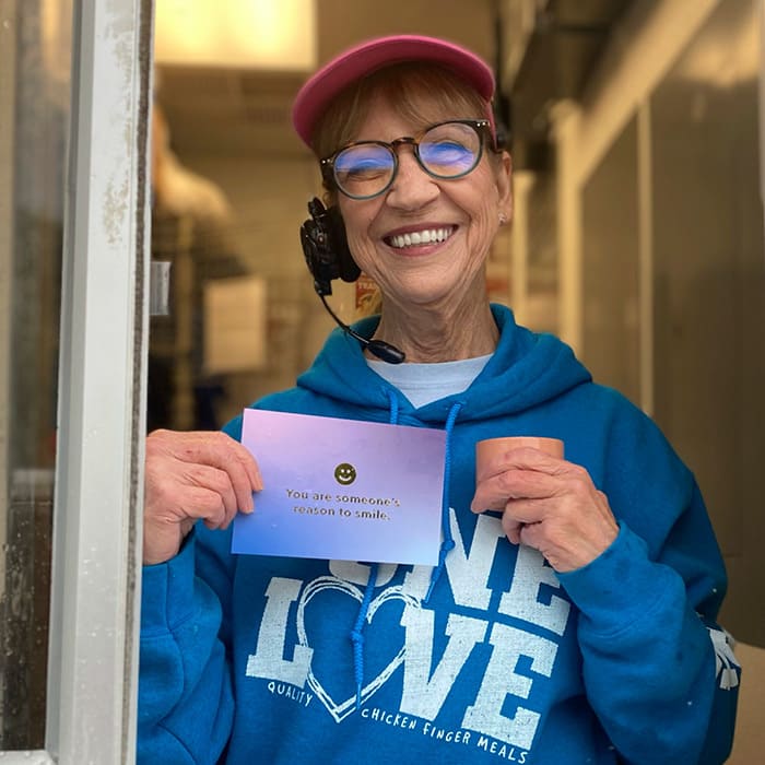 A drive-thru worker smiling after receiving a compliment postcard