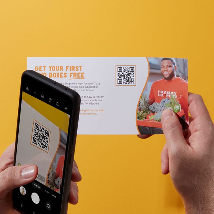 A flyer with a QR code design being scanned by a mobile phone. 
