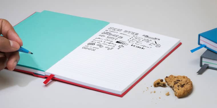 MOO red hardcover work notebook laid open with a person doodling and making notes inside, showing example of notebook organization